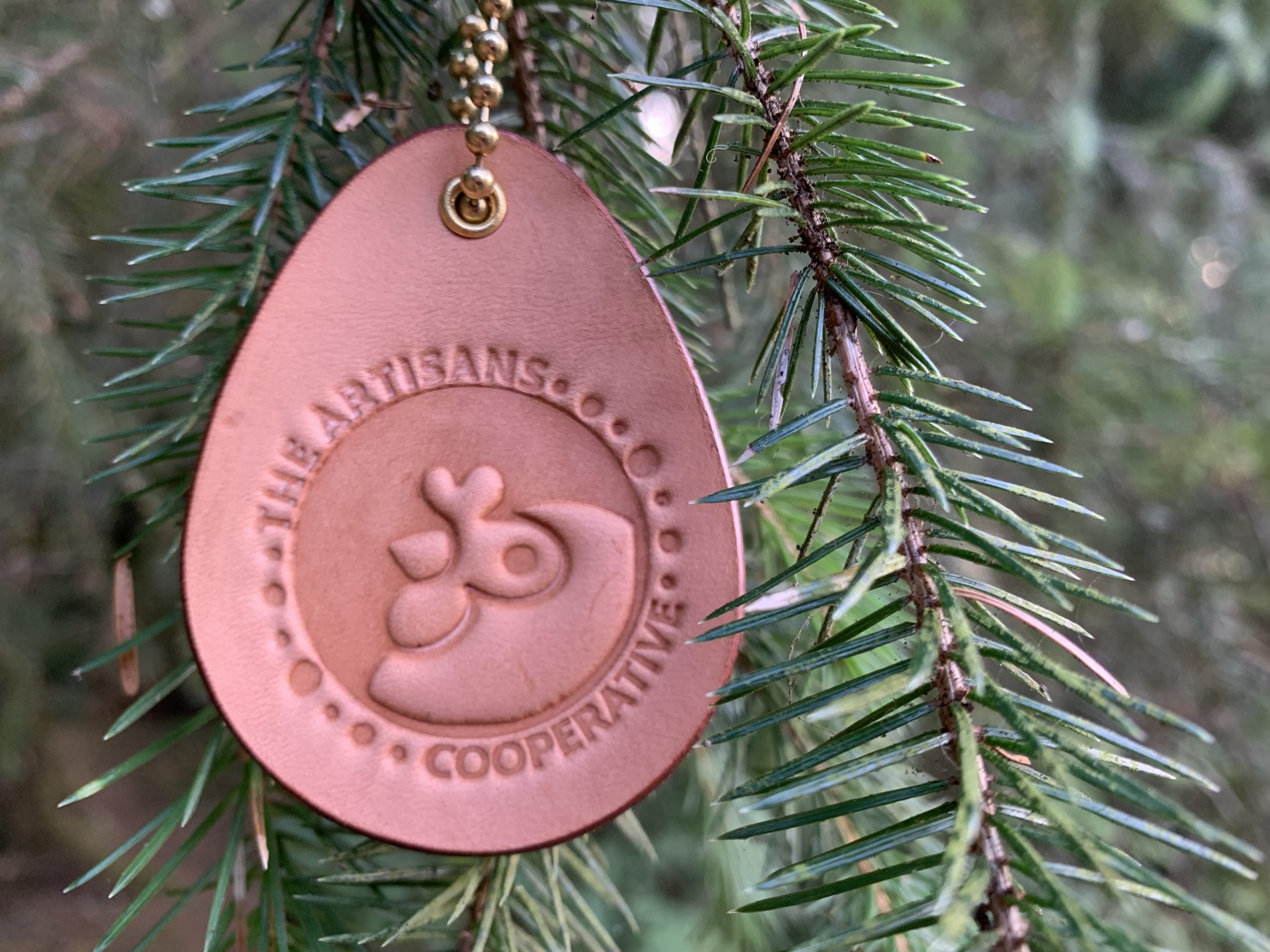 Leather Ornament Hanging from Tree with Artisans Cooperative Logo