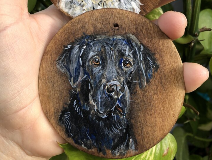 Photo of circular piece of wood with a black dog hand painted on it.