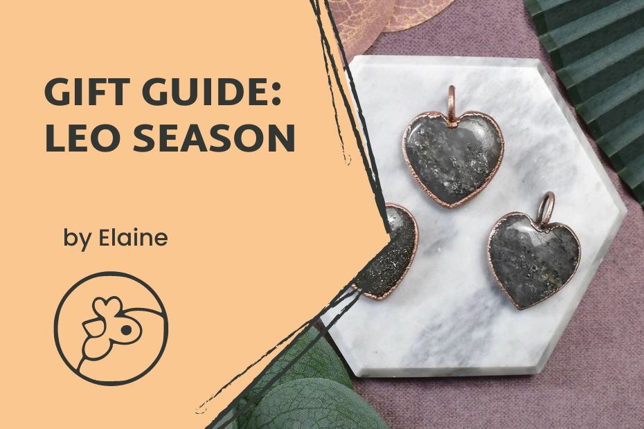 Text reads :Gift Guide: Leo Season, by Elaine" with the Co-op chicken symbol on a light orange hexagon corner over a picture of three stone heart shaped pendants.